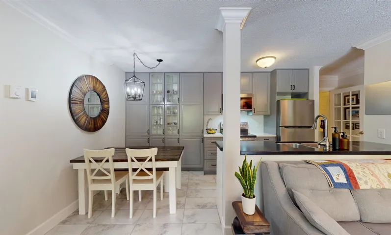 Living room with ornamental molding, light marble finish flooring, baseboards, a textured ceiling, and a chandelier