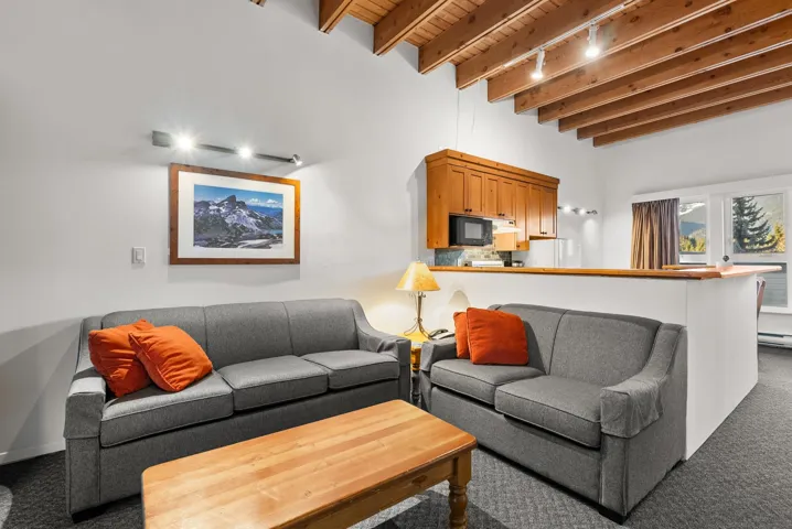 Carpeted living room featuring a wood ceiling with exposed beams and track lighting
