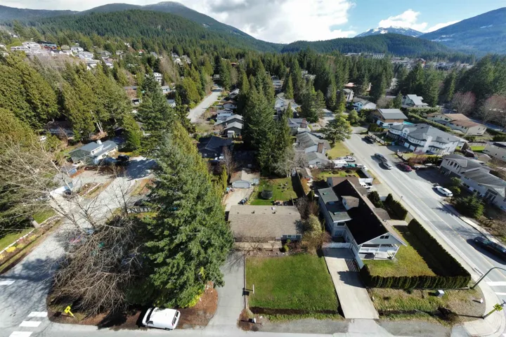 Aerial perspective of suburban area featuring a mountainous background and a heavily wooded area