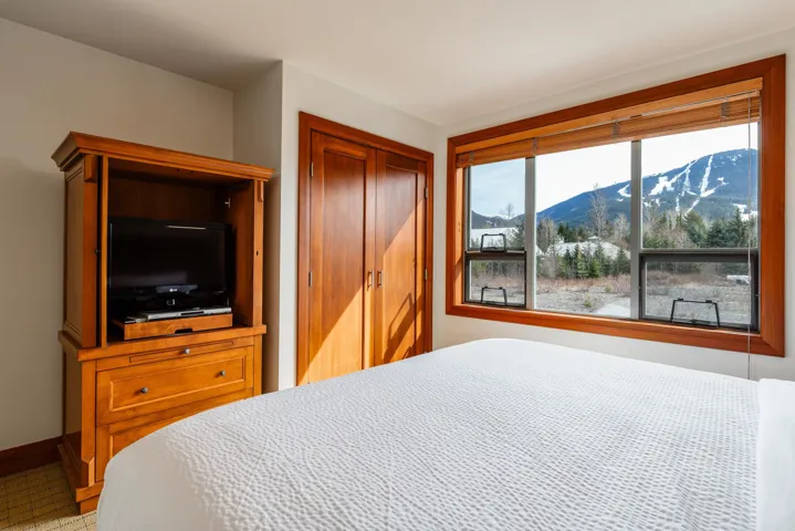 Bedroom featuring expansive window with natural wood trim, showcasing mountain scenery