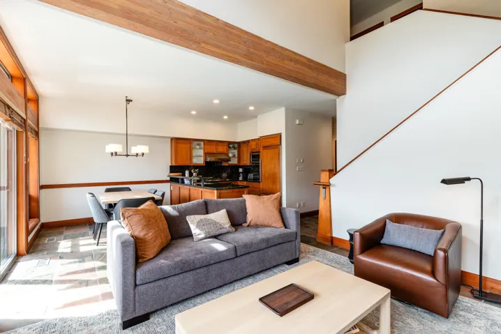 Open-concept living space featuring a prominent wood beam, high ceilings, and a two-story wall