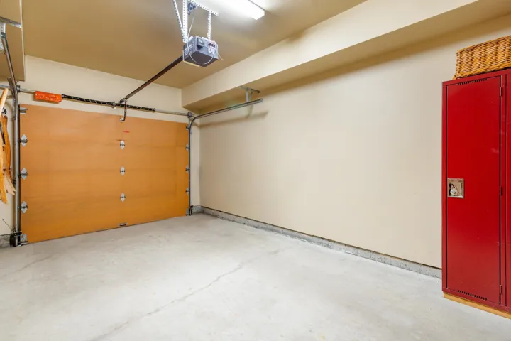 Spacious garage featuring a light wood-finish garage door, concrete flooring, and an overhead garage door opener