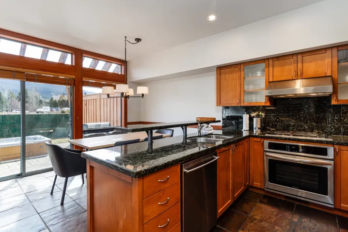Kitchen featuring wood-finish cabinetry, dark granite countertops, stainless steel appliances, and a built-in breakfast bar