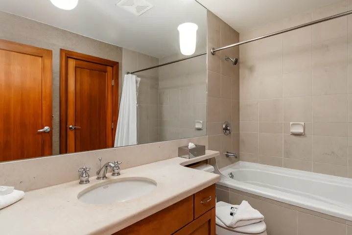 Contemporary bathroom featuring a light-toned vanity with an integrated sink, polished chrome fixtures, and a spacious mirror