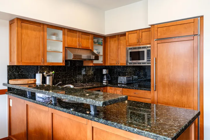 Kitchen featuring rich wood cabinetry, dark speckled countertops, and a built-in stainless steel microwave