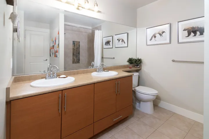 Full bathroom with double vanity, tile patterned flooring, a sink, and toilet
