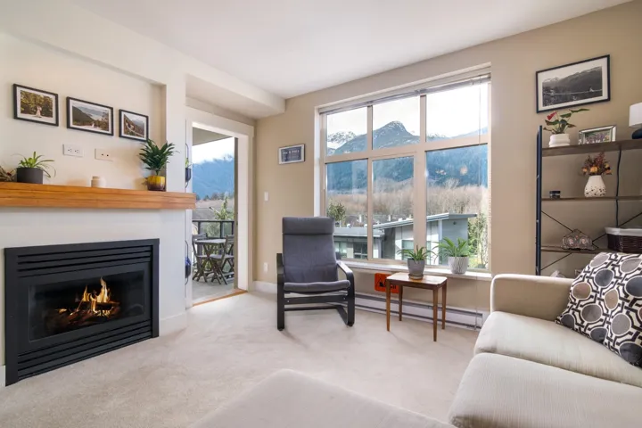 Carpeted living area with a baseboard heating unit, a glass covered fireplace, a mountain view, and baseboards
