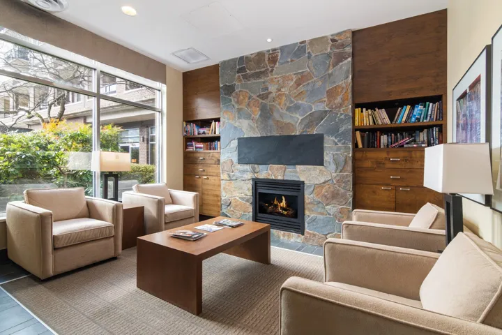 Living room with built in features and a stone fireplace