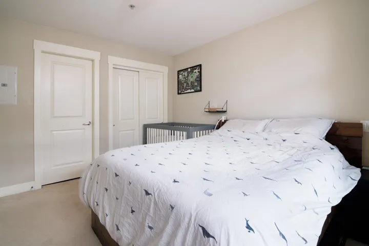 Bedroom with a closet, light colored carpet, electric panel, and baseboards