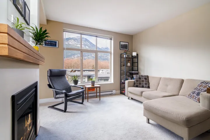 Living area featuring baseboard heating, carpet, a glass covered fireplace, and baseboards