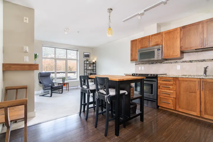 Kitchen featuring brown cabinetry, dark wood-style floors, a sink, stainless steel appliances, and backsplash