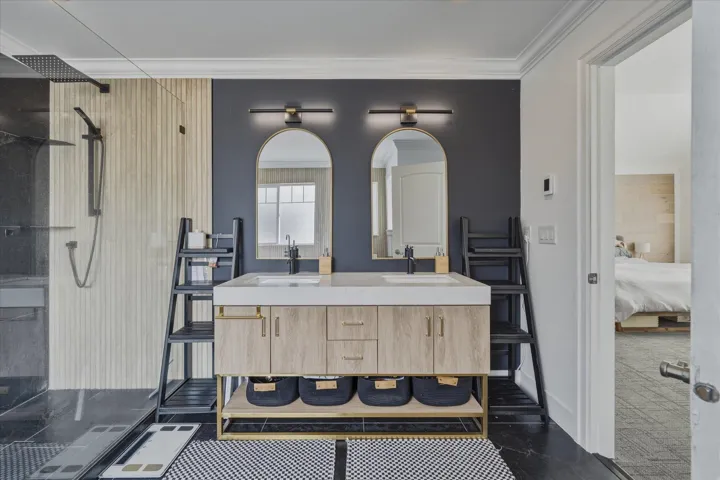 Double vanity with light wood-finish cabinetry, white countertop, and dual arched mirrors with matte black fixtures