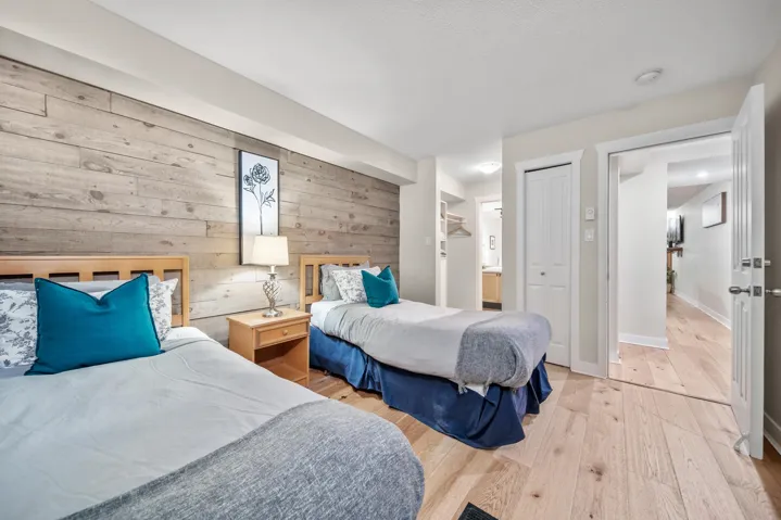 Bedroom with wood walls, light wood-type flooring, baseboards, a closet, and ensuite bathroom