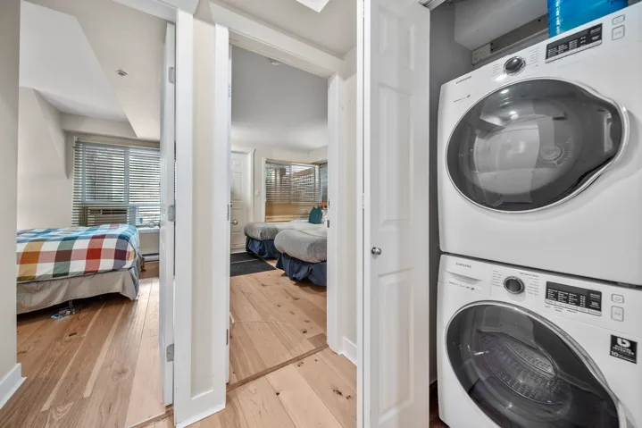 Washroom featuring stacked washer / drying machine and hardwood / wood-style flooring