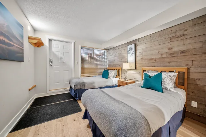 Bedroom featuring wooden walls, wood finished floors, baseboards, and a textured ceiling