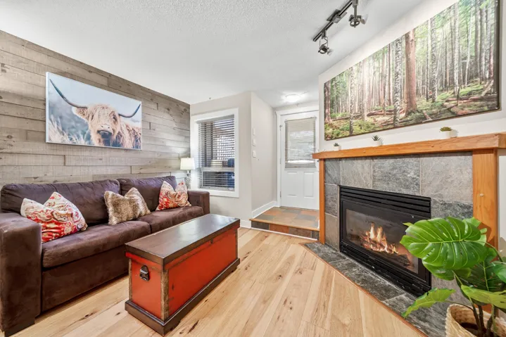 Living area featuring wooden walls, a tiled fireplace, wood finished floors, a textured ceiling, and an accent wall