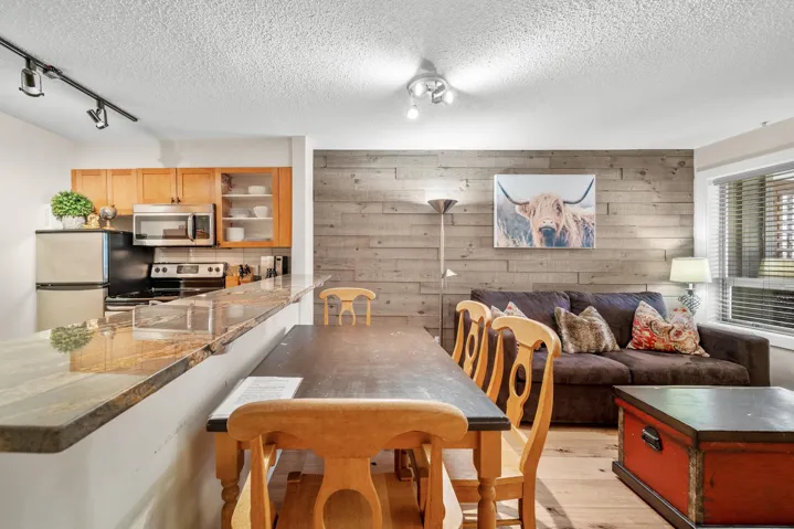 Dining space with a textured ceiling, rail lighting, light wood finished floors, and wooden walls