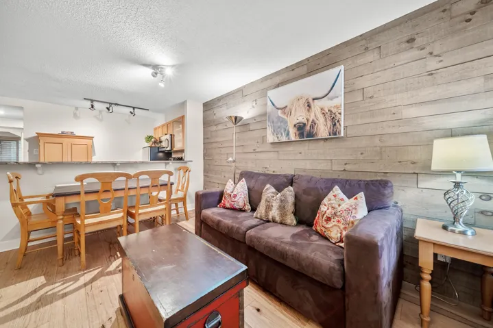 Living area with wooden walls, light wood-type flooring, baseboards, a textured ceiling, and rail lighting