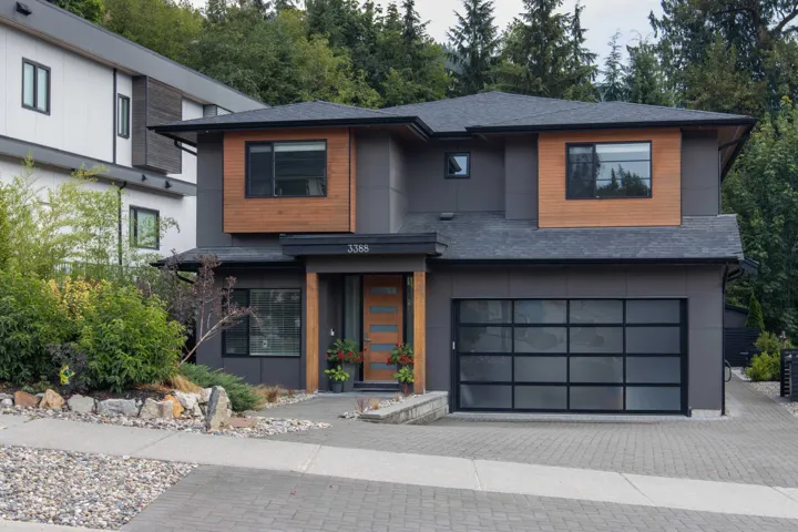 Contemporary home featuring a shingled roof, a garage, and decorative driveway
