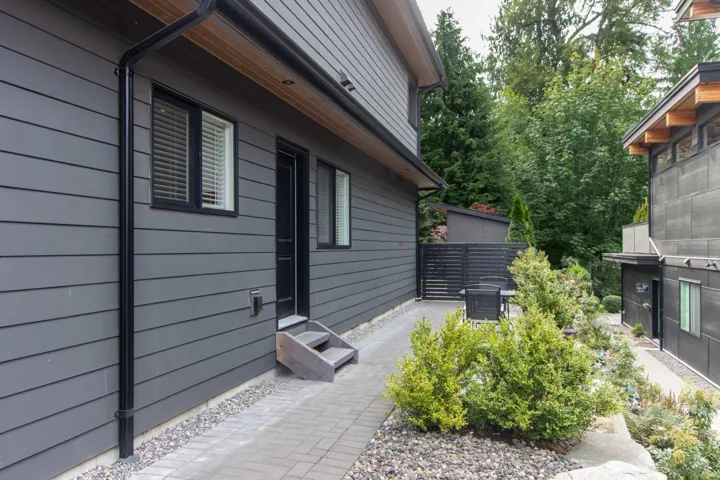 Kitchen with appliances with stainless steel finishes, white cabinets, light wood finished floors, under cabinet range hood, and light stone counters