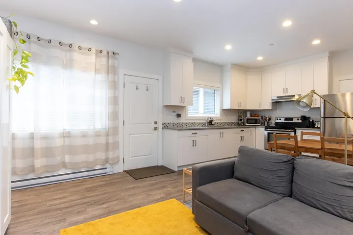 Laundry area with stacked washer / drying machine and dark wood finished floors