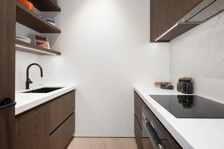 Kitchen with black electric cooktop, stainless steel oven, light wood-type flooring, open shelves, and under cabinet range hood