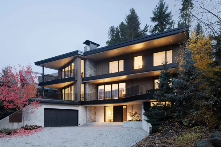 Contemporary house featuring stone siding, decorative driveway, a balcony, and an attached garage