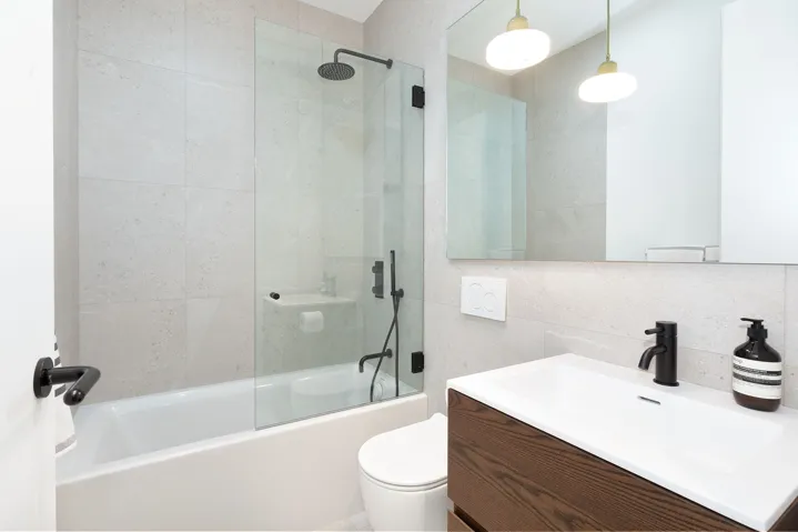 Bathroom with tile walls, combined bath / shower with glass door, vanity, and backsplash