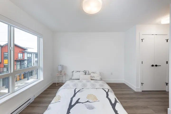 Bedroom featuring baseboards, wood finished floors, a baseboard heating unit, and a closet