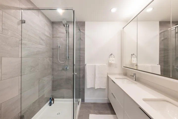 Full bathroom featuring double vanity, a sink, and a shower stall