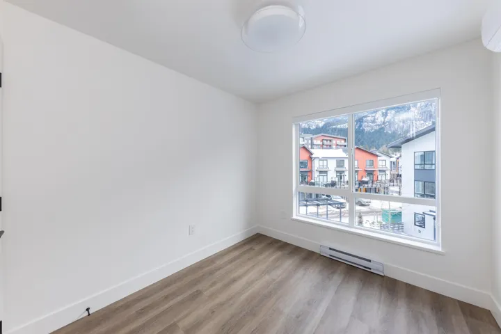 Empty room with baseboards, an AC wall unit, wood finished floors, and a baseboard heating unit