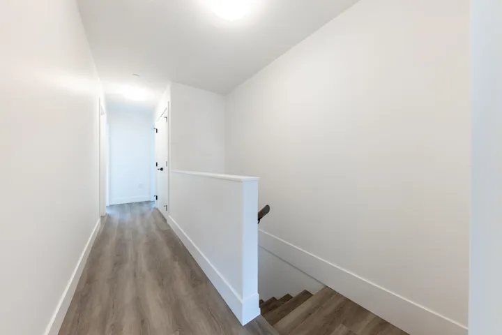 Corridor featuring baseboards, an upstairs landing, and wood finished floors