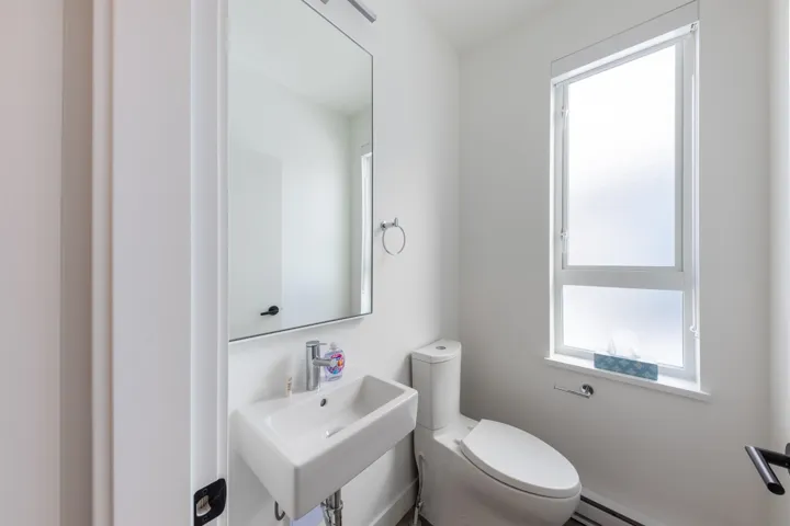 Half bathroom with a baseboard radiator, toilet, a sink, and a healthy amount of sunlight