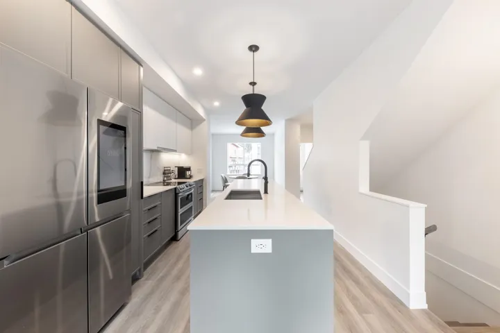 Kitchen featuring light countertops, modern cabinets, stainless steel appliances, a sink, and gray cabinets