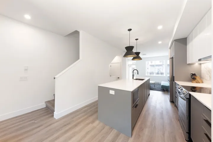Kitchen featuring light countertops, a sink, light wood-style floors, a kitchen island with sink, and appliances with stainless steel finishes