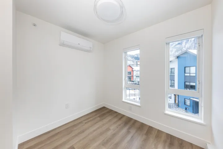 Unfurnished room featuring light wood finished floors, baseboards, and a wall mounted AC