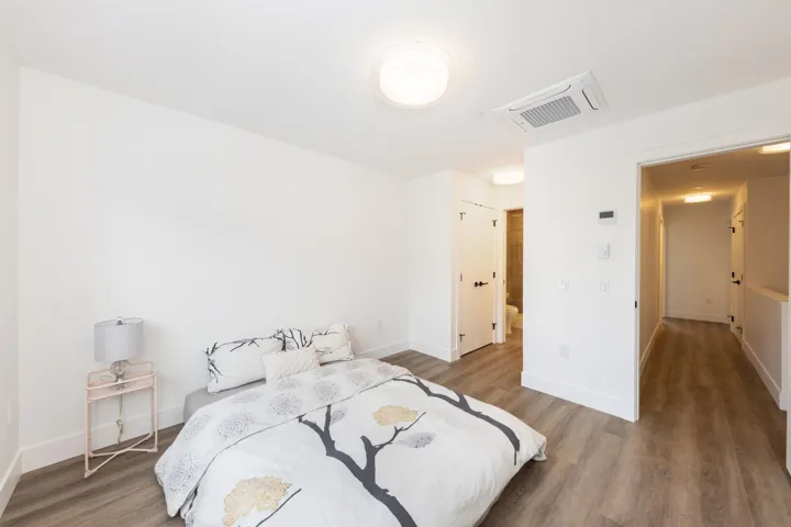 Bedroom with wood finished floors, baseboards, and visible vents