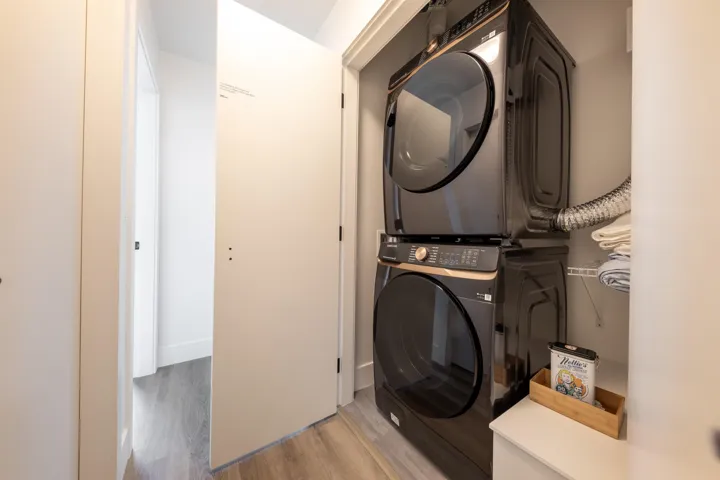 Laundry room featuring light wood-type flooring, stacked washing maching and dryer, and laundry area
