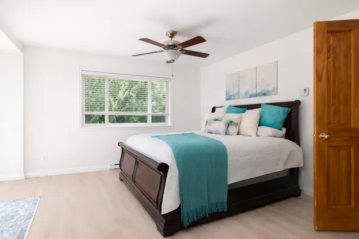Bedroom featuring light wood-style flooring, ceiling fan, and a baseboard heating unit