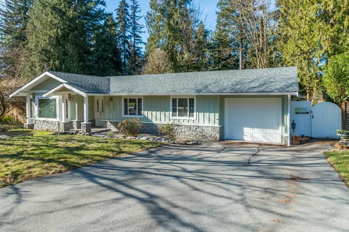 Ranch-style home featuring asphalt driveway, a shingled roof, a garage, a gate, and board and batten siding