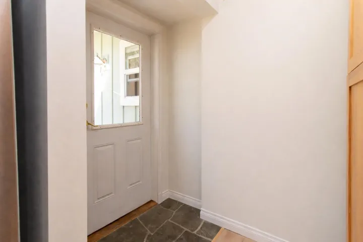 Doorway to outside featuring stone finish floors and baseboards