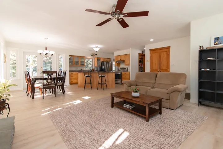 Living area with suspended lighting, a ceiling fan, and light wood-type flooring