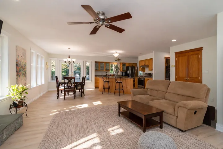 Living room featuring light wood-style floors, ceiling fan, and a chandelier