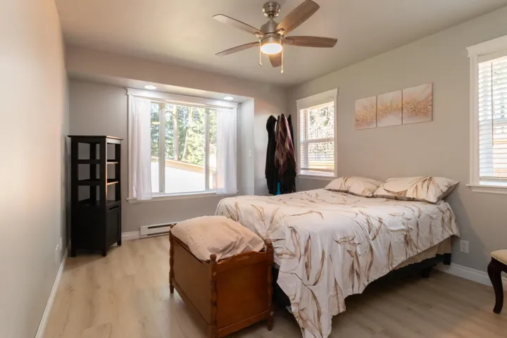 Bedroom with light wood finished floors, ceiling fan, and a baseboard radiator