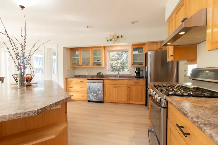 Kitchen with stainless steel appliances, glass fronted cabinets, light wood finished floors, recessed lighting, and light countertops