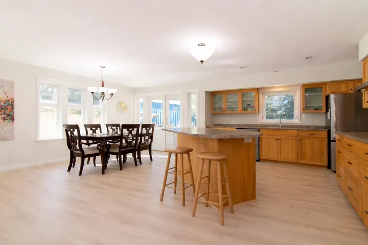 Kitchen with a breakfast bar, glass fronted cabinets, a center island, dark countertops, and stainless steel appliances