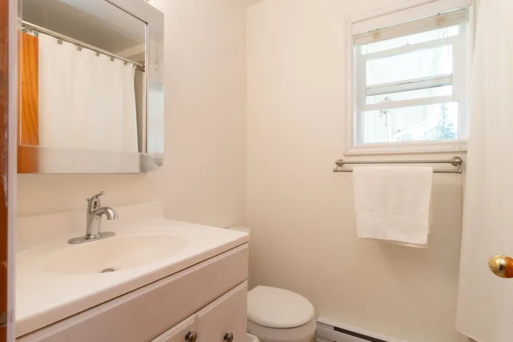 Full bath featuring vanity, curtained shower, and a baseboard heating unit