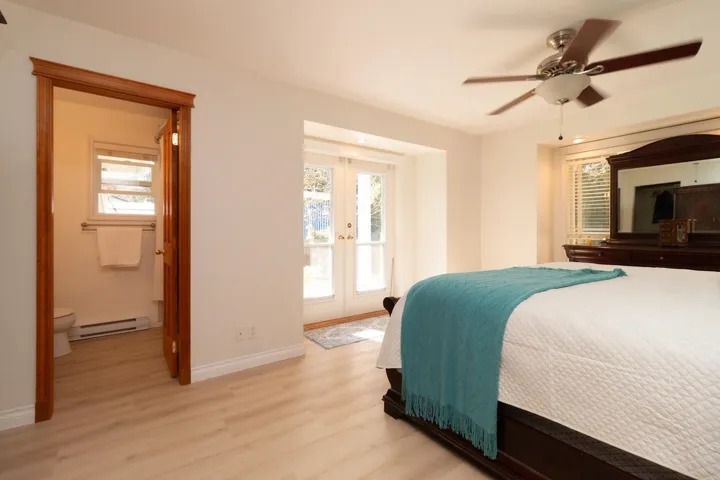Bedroom featuring light wood-type flooring, baseboard heating, access to exterior, ceiling fan, and french doors