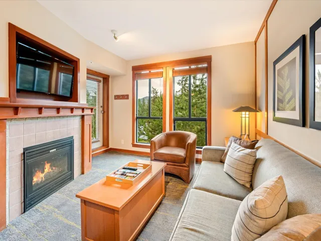 Carpeted living area with a tile fireplace and baseboards
