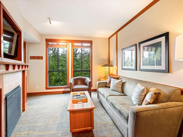 Carpeted living area with a tile fireplace and baseboards